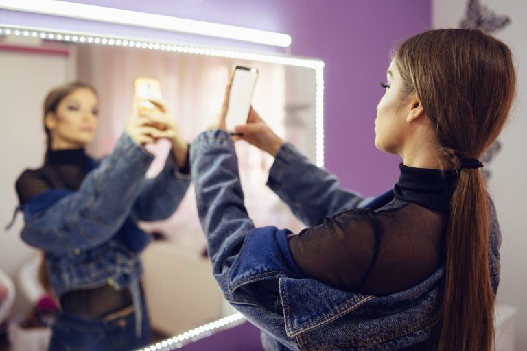 Mujer tomando foto con el teléfono viéndose al espejo
